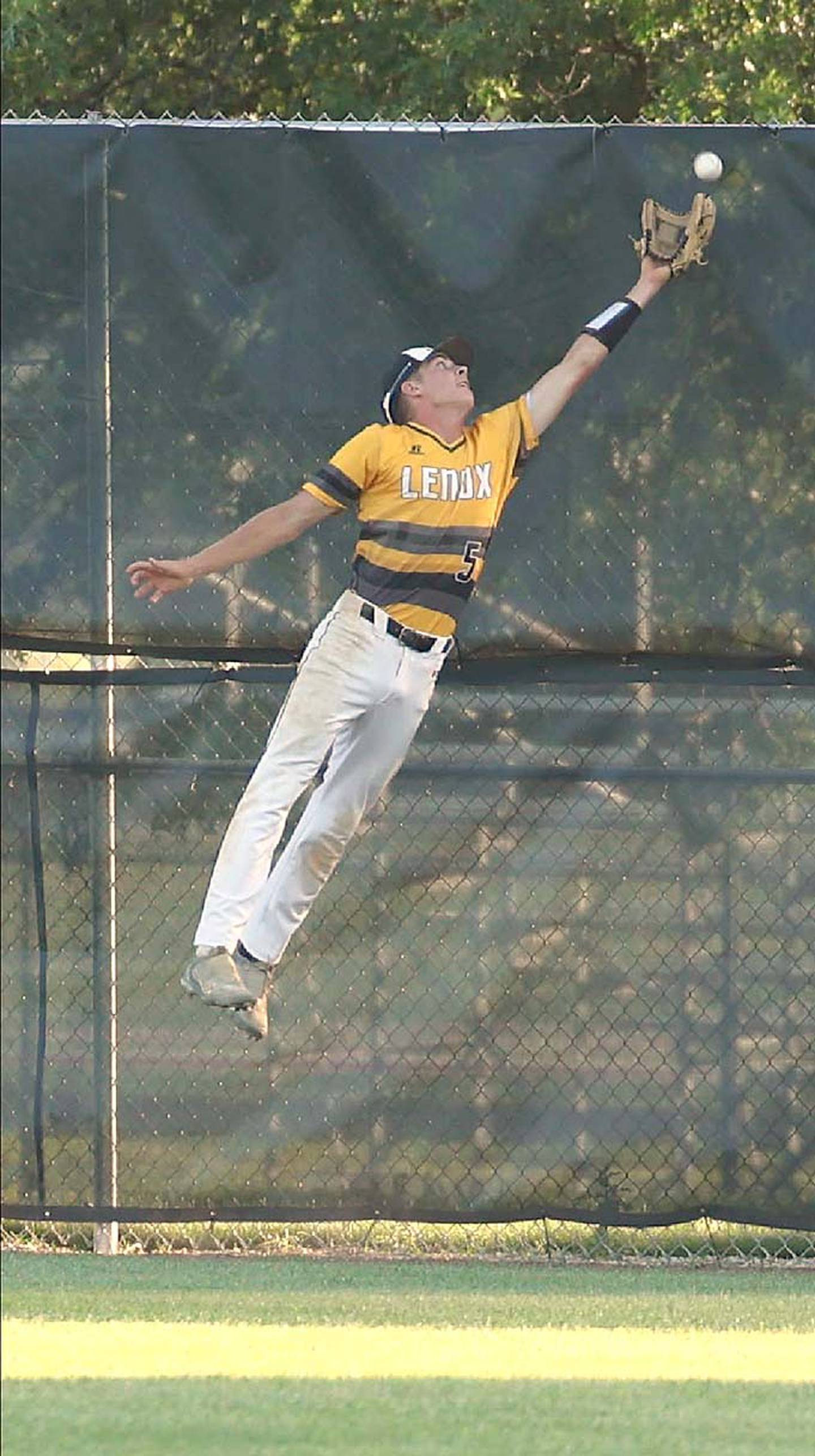 Gabe Funk leaps to reach for a drive to the fence as Lenox's center fielder.
