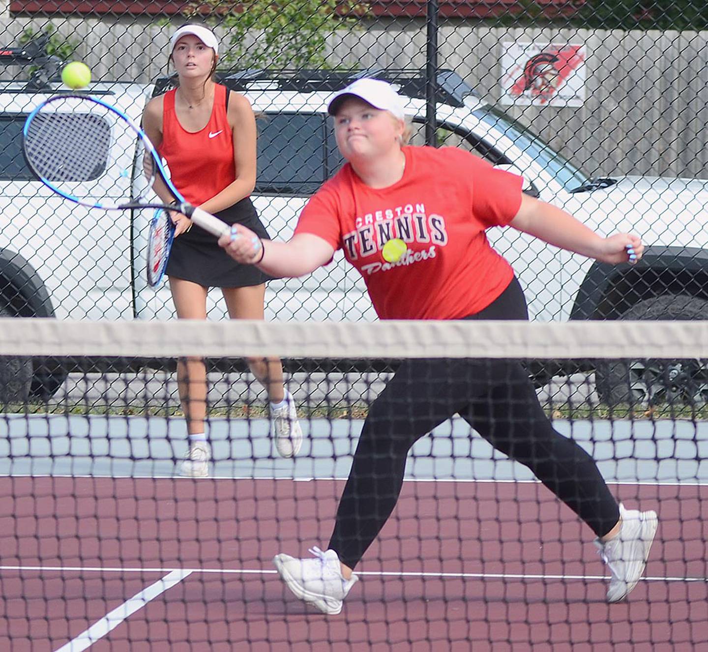 Brooke Huck of Creston punches a volley across the net as doubles teammate Savannah Jaques watches from the baseline.