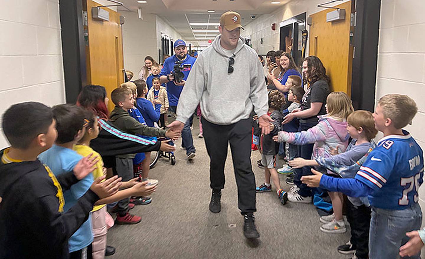 A Buffalo Bills video camera operator follows Spencer Brown's walk through the Lenox school hallways as Brown encounters a young student wearing his Bills No. 79 jersey.