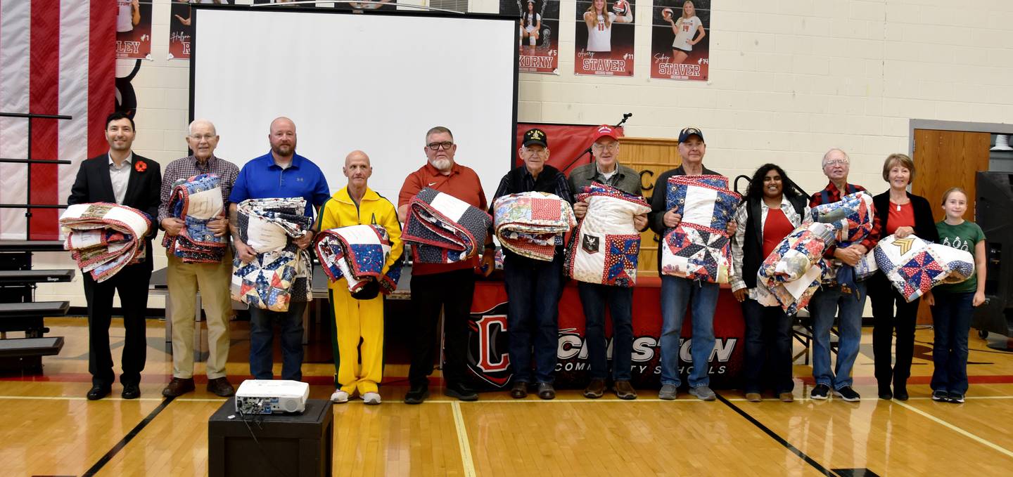 The 2025 Quilt of Valor recepients. From left, Brenden Kinyon (Army), James Francis (Navy), Jaryd Merritt (Army), Dennis Smith (Army), John Shiltz (Marine Corps), Robert Williams (Army), Roger Francis (Navy), John Giza (Navy), Grace Root (Army), Jerry Carson (Navy) and Syd Hudek and Estella Jondle on behalf of the late Bob Hudek (Army). Not pictured is Tim Rankin, Army. The quilts are handmade each year by Margaret Kneedler.