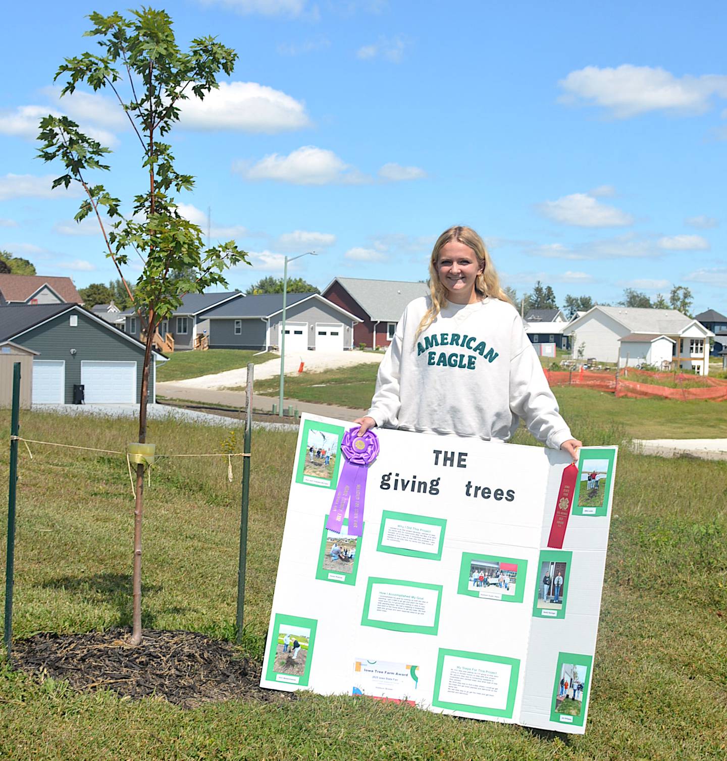Addison Brewer with a tree she and the Summit Superstars 4-H Club planted in Greenfield. Brewer exhibited the project at the Adair County Fair and it qualified for the Iowa State Fair.