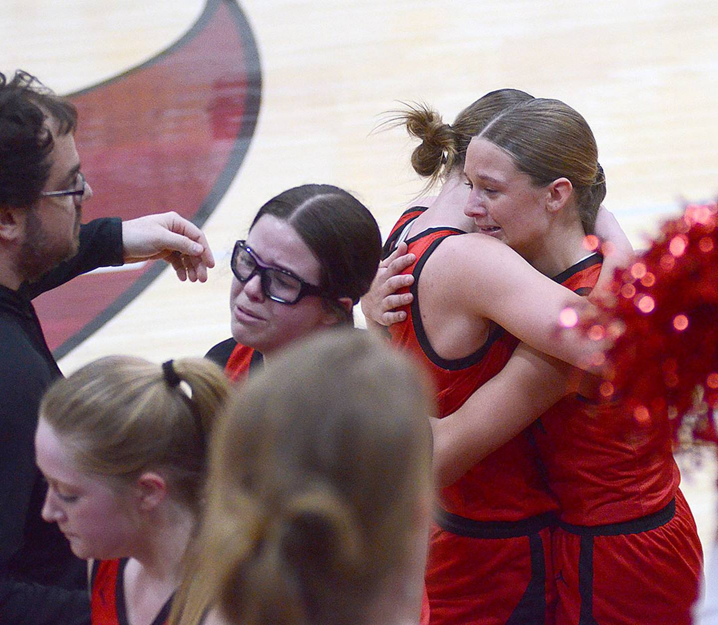 Creston seniors Kadley Bailey and Hollynn Rieck embrace after Wednesday's loss. Also shown at left are assistant coach Bryant McCabe, Brynn Tussey and Braylee Pokorny.