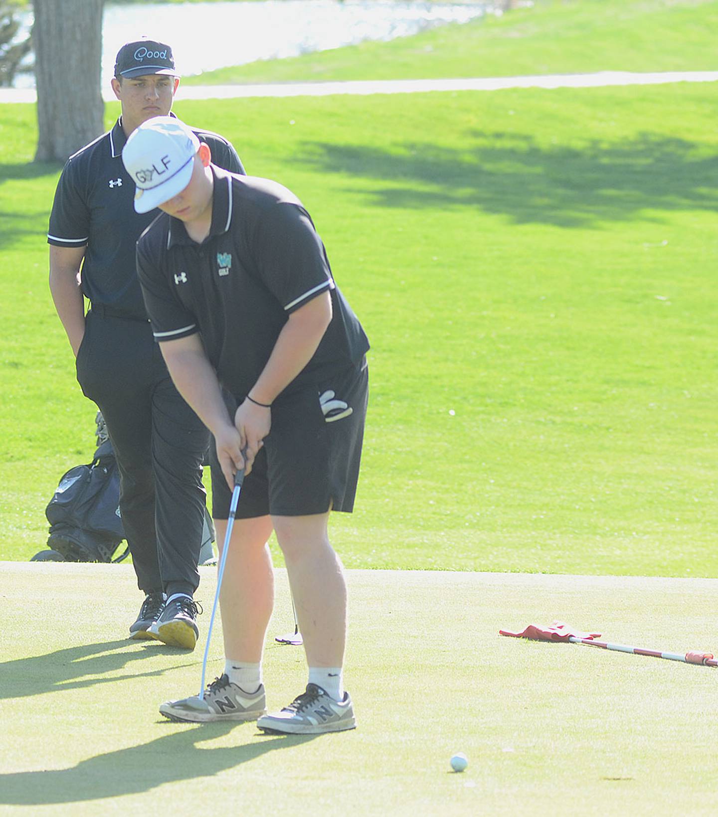 Ethan Johnston of Southwest Valley putts on No. 9 at Crestmoor Monday as teammate Casey Jones looks on.