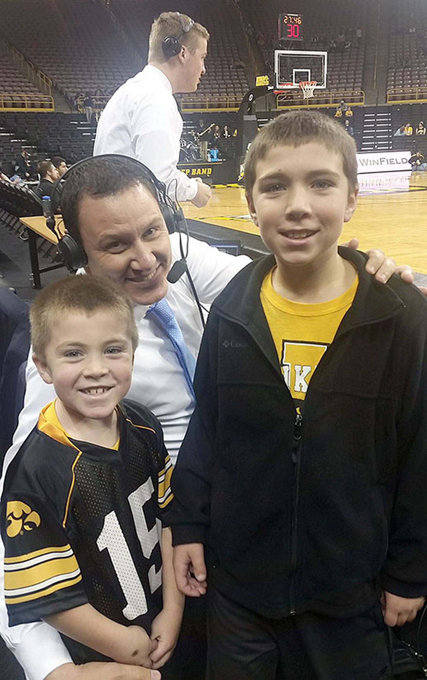Brothers Reece (right) and Carver (left) Hayes are shown with former Iowa Hawkeye basketball player Jess Settles courtside at a game several years ago. Settles works as a broadcast analyst for various networks, including the Big Ten Network.