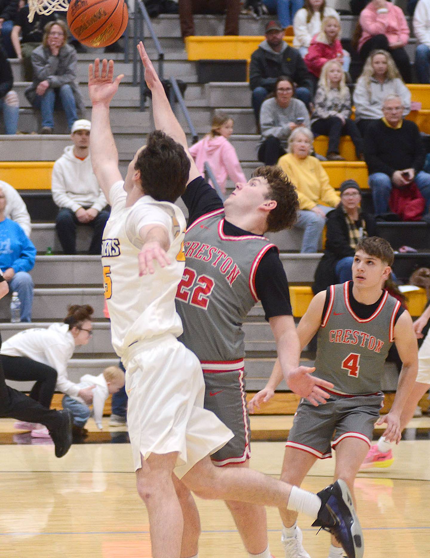 Creston's Nathan Carroll contests a drive to the basket by Knoxville guard Lincoln Norris.