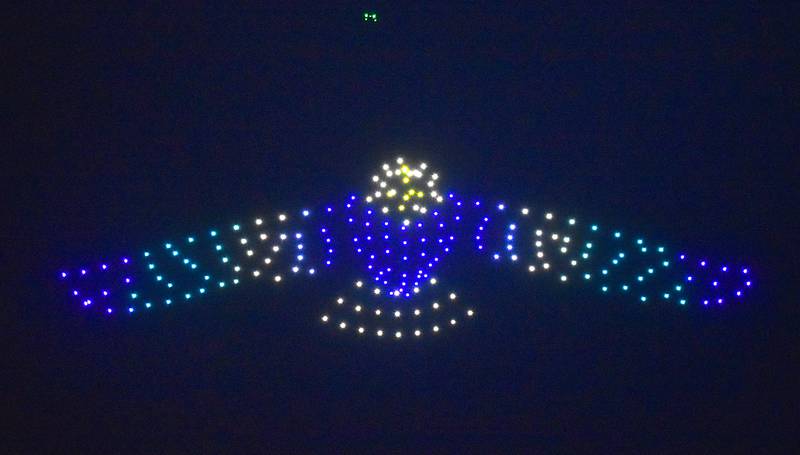 An eagle flaps its wings. The eagle is actually made up of over a hundred drones, lighting up the night sky over East Union's football field.