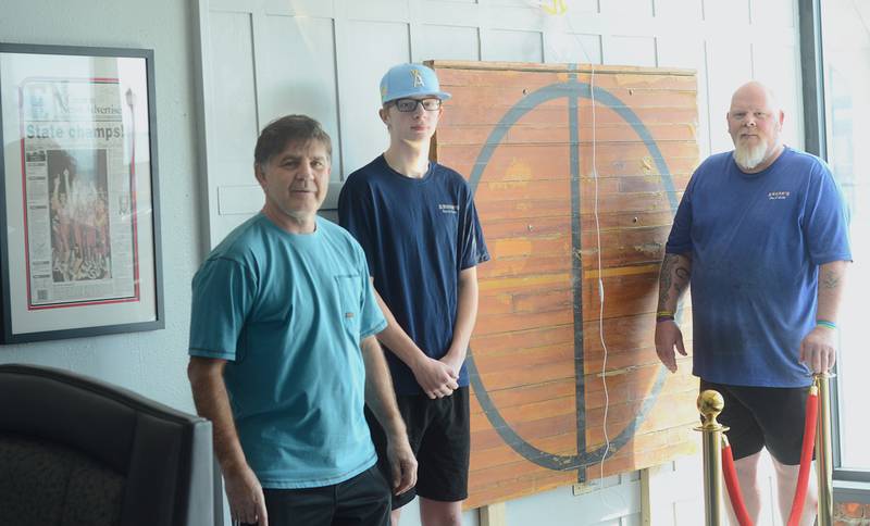 A display of Creston and area basketball history, including the center jump circle from the former high school at Irving and Maple streets, will be unveiled May 4 at Anson's Bar & Grill. Shown from left are event organizer John Walters, Logan Anson and Joe Anson. The framed photo at left is the News Advertiser front page from the boys state championship in 1997.
