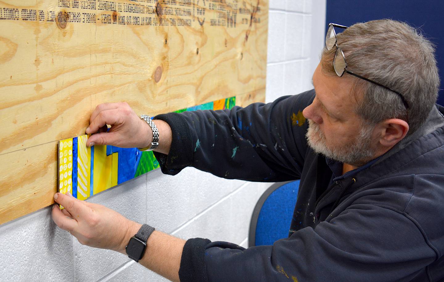 Greg Preslicka, the designer for the mural, installs each square of the mural before doing a final cleanup.