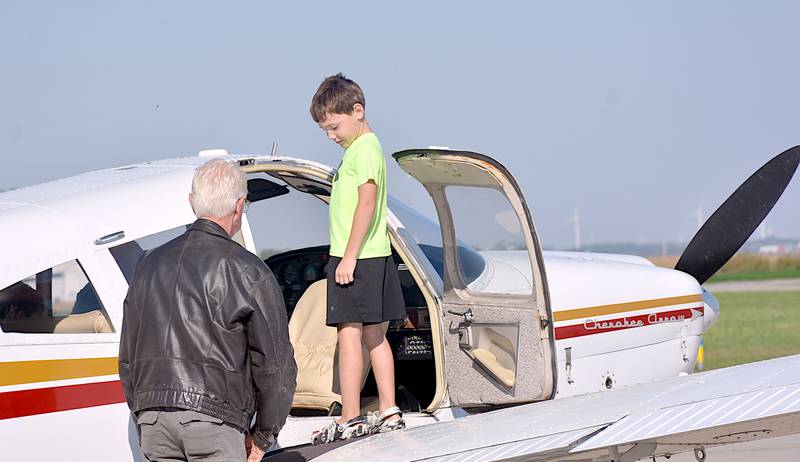 Iowa Aviation Museum President Greg Schildberg, left, helps a child into an airplane for plane rides Saturday at the Greenfield airport.