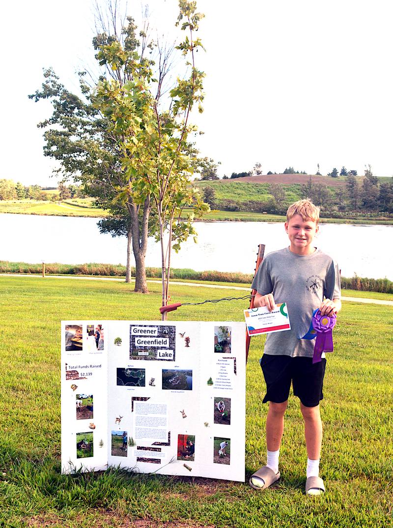 Harper Wright, next to one of the trees he planted at Lake Greenfield with the help of his grandfather Brian Hoadley as a 4-H project.