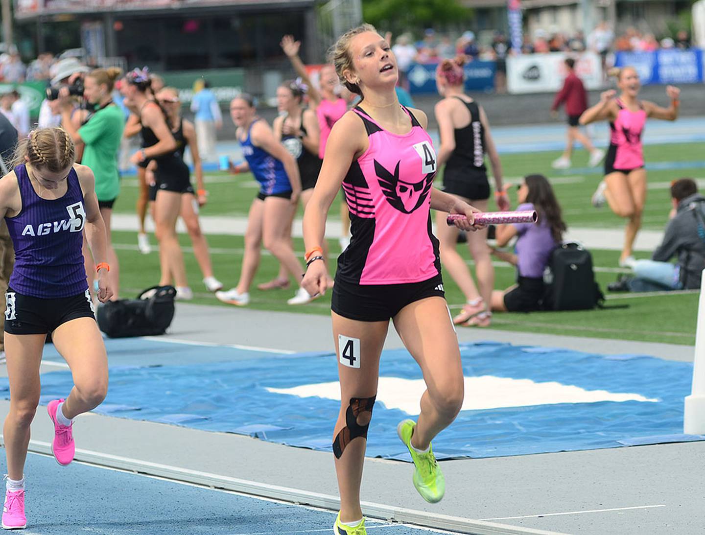 Mount Ayr's Emma Reynolds holds off the charge of Piper Smith of AGWSR to cross the finish line first in the 4x400 relay, the final event of the state meet. Mount Ayr had a winning time of 3:59.84 to clinch the second-place team trophy in Class 1A. Reynolds' relay teammates are seen celebrating in the background.