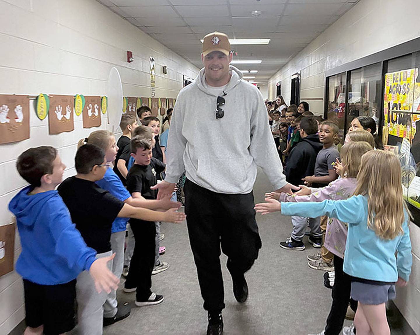 Spencer Brown gives "high fives" as he walks down the Lenox Elementary School hallway Friday. A Buffalo Bills video crew accompanied Brown on his visit home to Lenox.