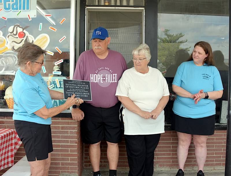 From left, Catherine Olesen of the Greenfield Historic Preservation Commission presents David, Kendalyn and Katie Huff with a plaque designating Tiger Drive-In in Greenfield as a member of the National Register of Historic Places.