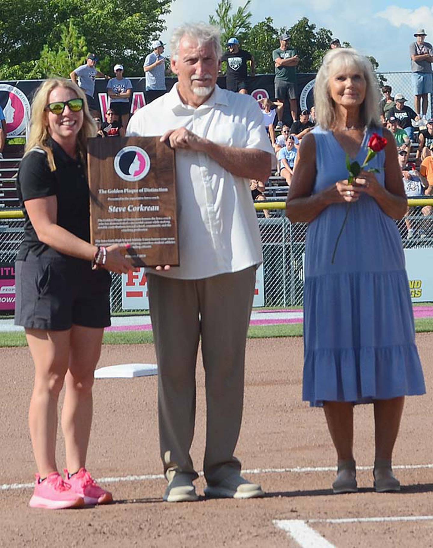 Former Winterset softball coach Steve Corkrean, accompanied by wife Nancy, receives the Golden Plaque of Distinction from Erin Gerlich, executive director of the Iowa Girls High School Athletic Union.