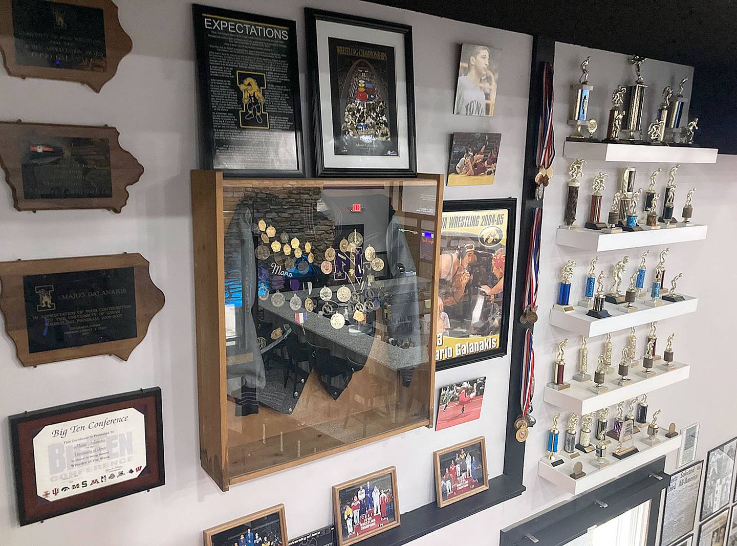 A display of wrestling memorabilia from Mario Galanakis' career, including as a starter for the Iowa Hawkeyes, is shown along a stairwell to an upstairs dining area at the restaurant.