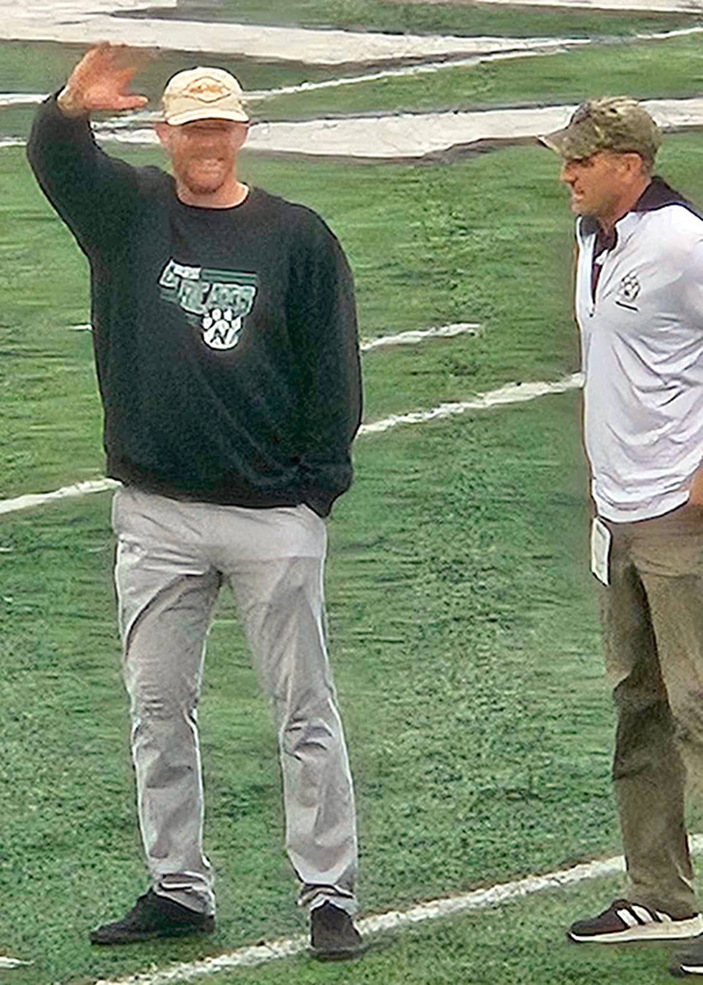 Hall of Fame inductee Collin Bevins waves to fans as he's introduced at halftime of the Oct. 25 homecoming football game. Dr. Andy Peterson, Northwest Missouri State athletic director, is at right.