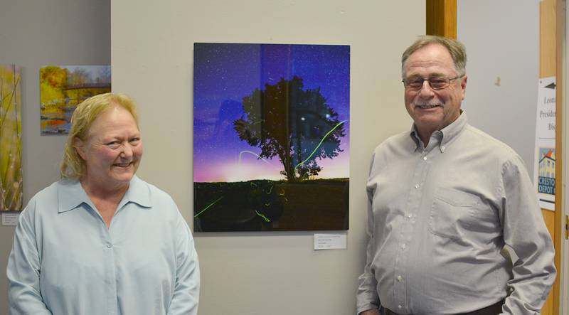 Kathleen, left, and Gary Hoard, right. The photo in the center, "Fireflies on an Iowa Summer Night" taken by Gary at Big Creek State Park, has fireflies leaving trails of green light, an illusion left behind on the digital photograph.