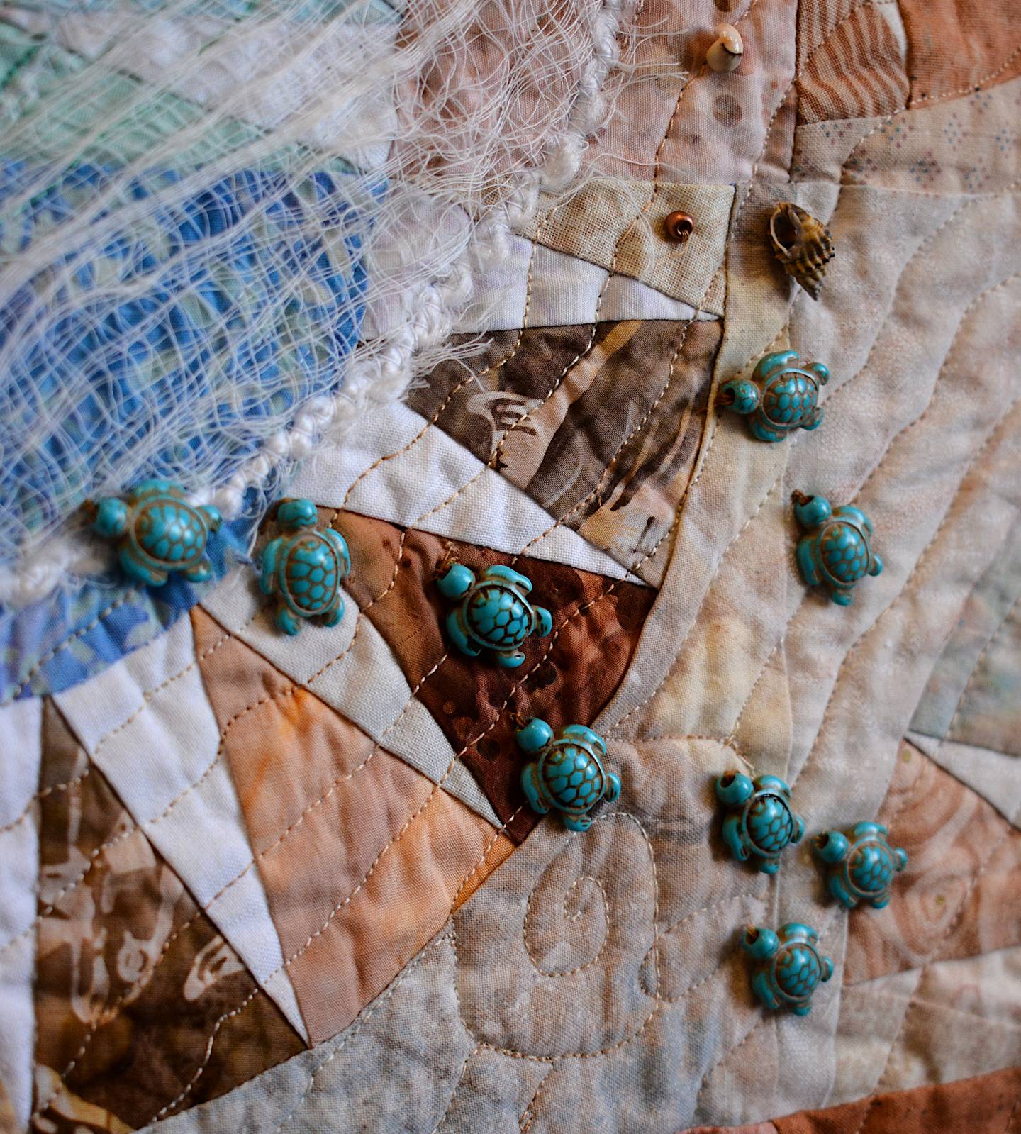 Small miniature turtles are attatched to a quilt, one of the many examples of breaking the norms of quiltmaking in the Quilt Rebels exhibit.
