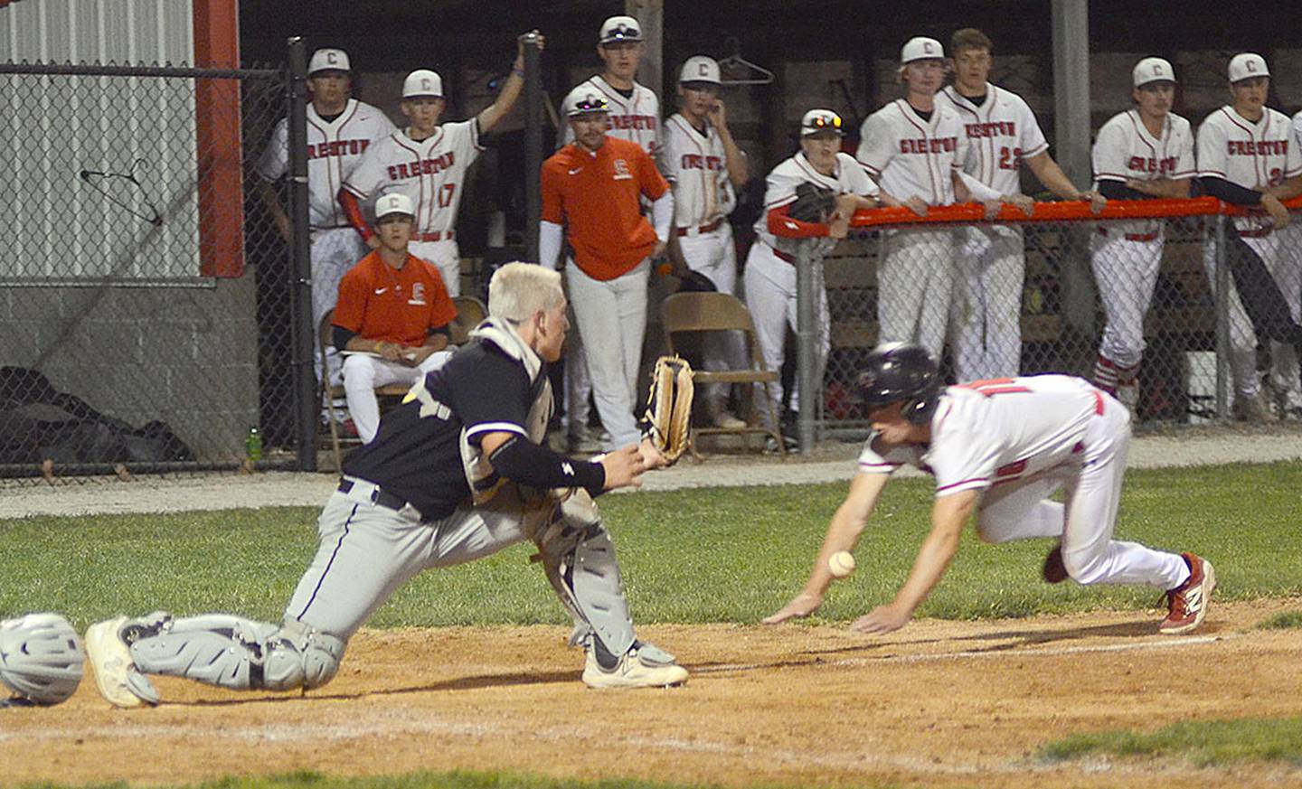 Tyler Riley of Creston dives to score the winning run in the 10th inning after a Glenwood error on a ground ball hit by Brady McDonald. Riley drew a leadoff walk to start the rally.