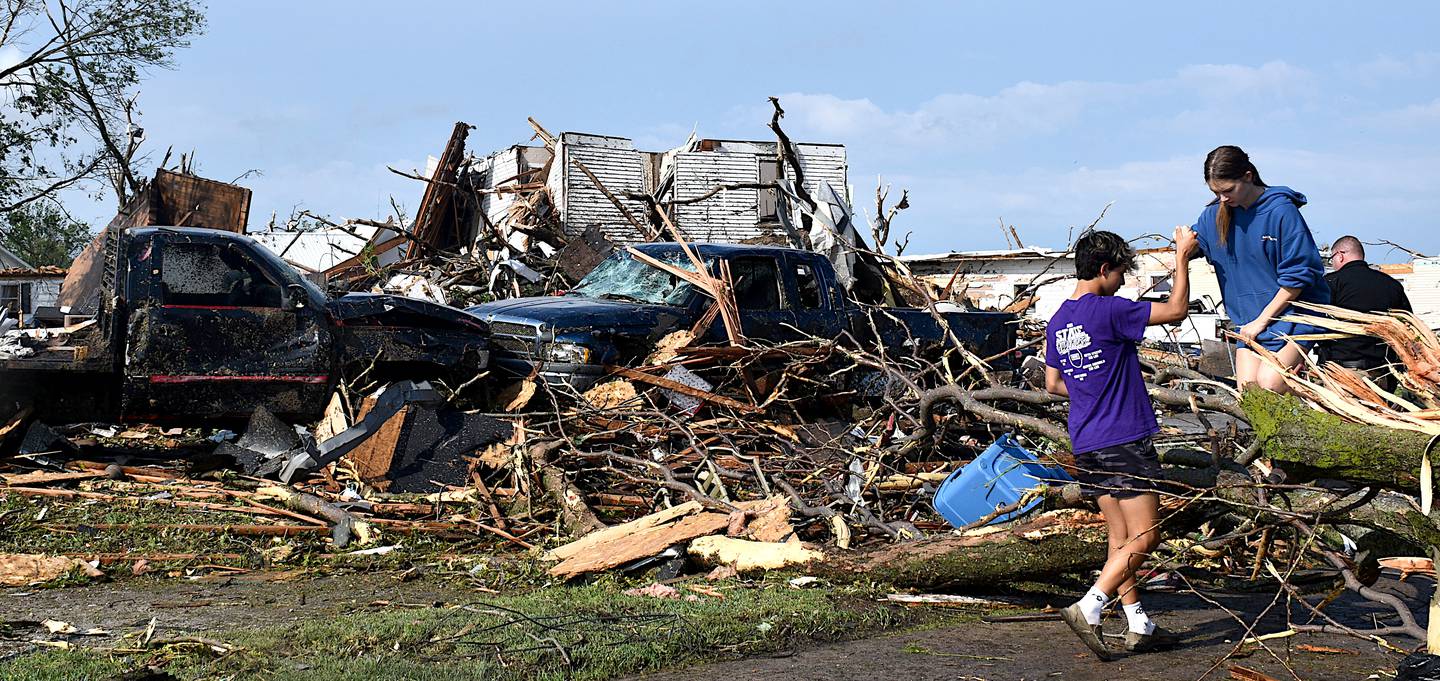 A family sifts through the wreckage after Tuesday's storm, their vehicles damaged and home destroyed.