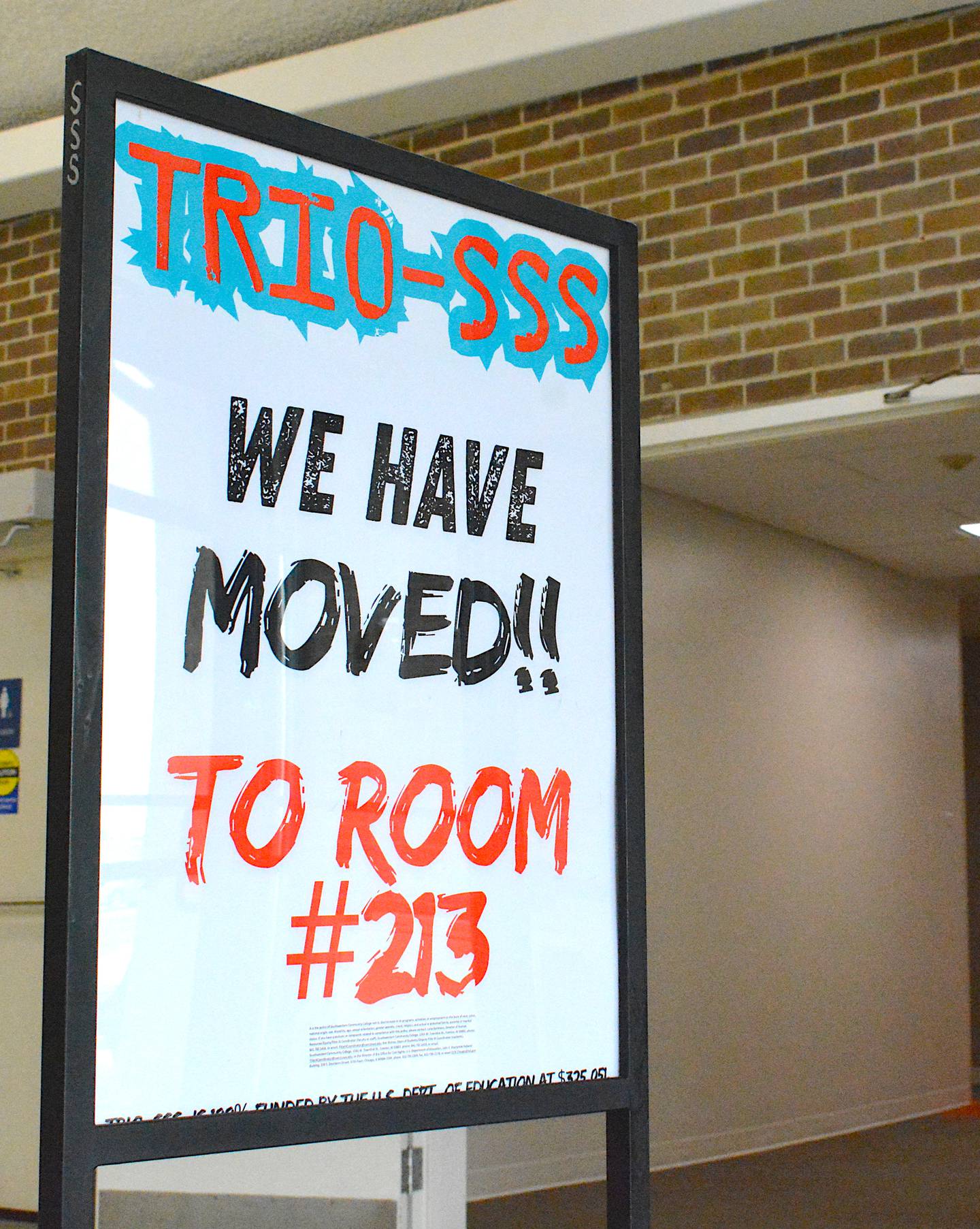 A sign in the SWCC Instructional Center informing students of the new location of TRIO Student Support Services at Room 213.