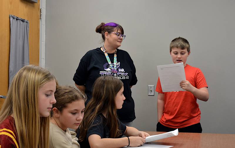 Nodaway Valley seventh-grader Max Antisdel (standing) practices his part for the middle school's Veterans Day Program with TAG instructor Gena Ward during class last week as Anna Herrick, Laila Hall and Marcella Hubenka follow along.