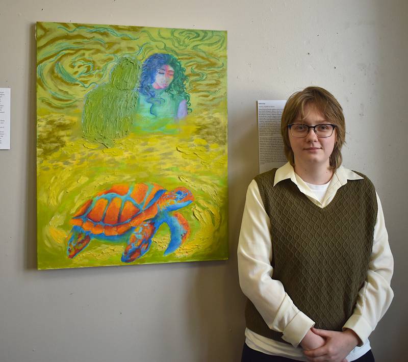 Robynn McKinney alongside their favorite piece in the exhibit, "Reflections."