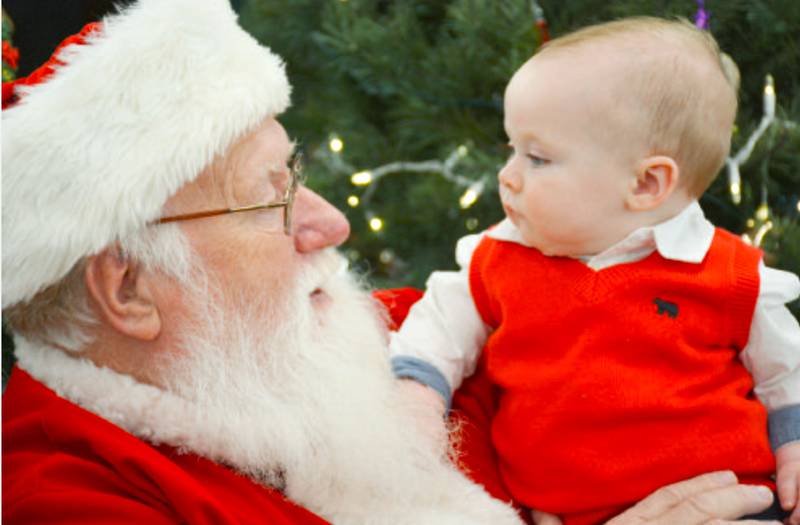 Six-month-old Jack Wolf runs his fingers through Santa's beard as Santa talks to him Saturday at Bomgaars in Creston. Wolf is the son of Tyler and Amanda Wolf.