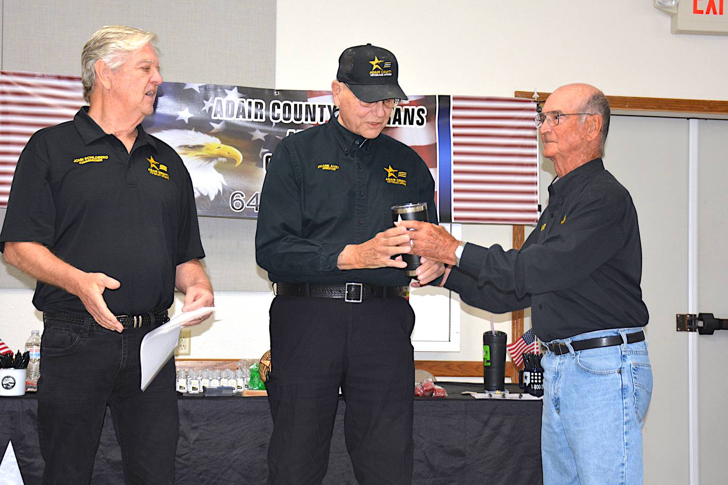 Lee Ashmore (right) and John Schildberg (left) present Duane Avey with a commemorative coffee mug upon his retirement as Adair County Veterans Affairs Director.