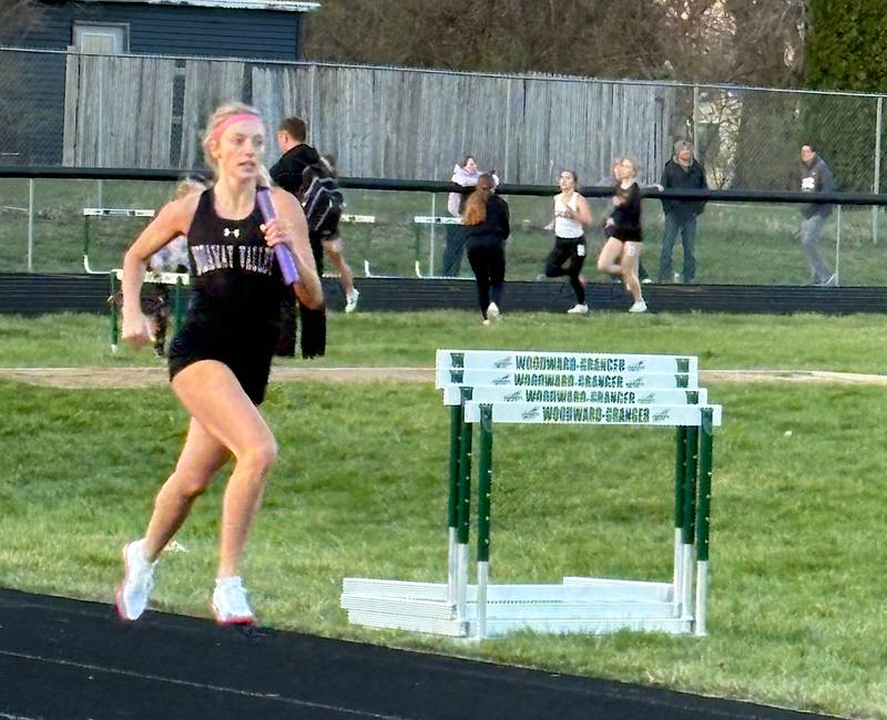 Wolverine senior Izzy Eisbach carries the baton down the straightaway in a relay race last week in Woodward.