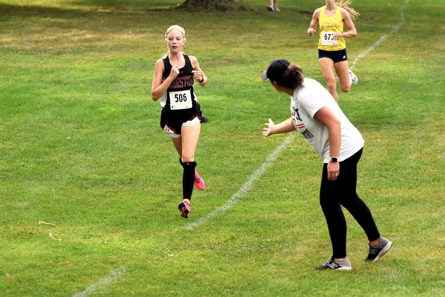 Coach Maggie Arnold cheers on Reese Strunk, a freshman who finished ninth in the girls race to take second for the Panthers.