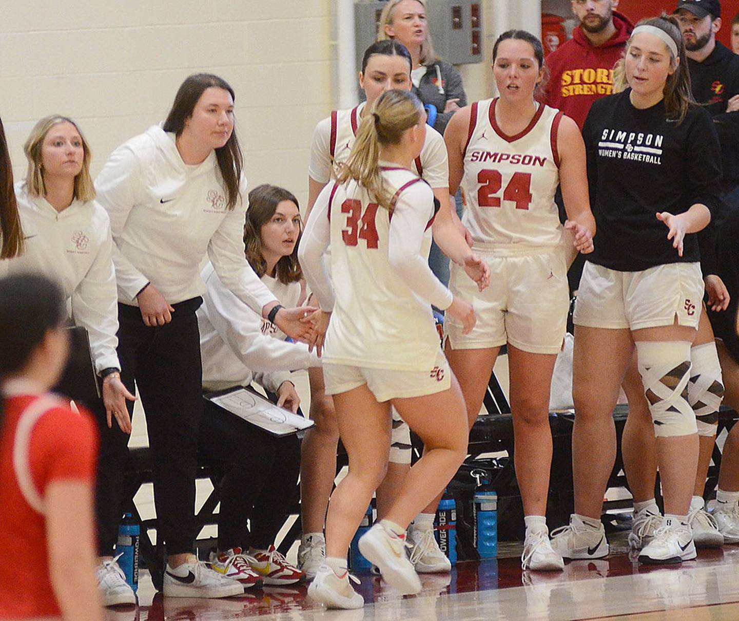 Simpson assistant coach Jenna Taylor (second from left) is in her fourth year as a member of the Storm coaching staff. She was an All-American player at Simpson. Also greeting Simpson's Ava Levings (34) to the bench is Doryn Paup (24).