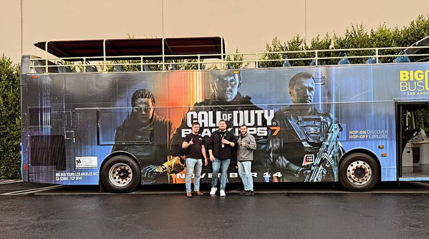 Nielsen and friends stand in front of a tour bus with an advertisement for "Black Ops 7."