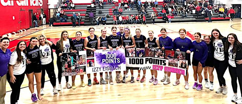 Nodaway Valley junior Izzy Eisbach (15) celebrates reaching 1,000 career points. with her teammates and coaches, after a win at Central Decatur Friday, Jan. 3.
