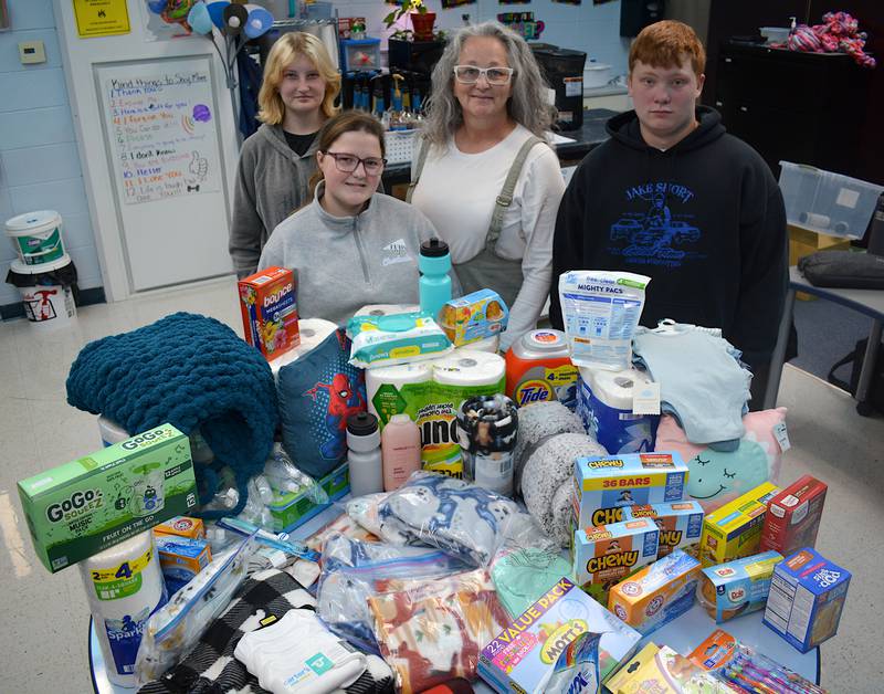 A few of the students and teacher Jean Kinyon, center, stand behind a few of the donations already collected for their trip to RMH children's hospitals. From left to right, Cora McNeill, Jocelyn McWilliams, Kinyon, Steven Jorgensen.
