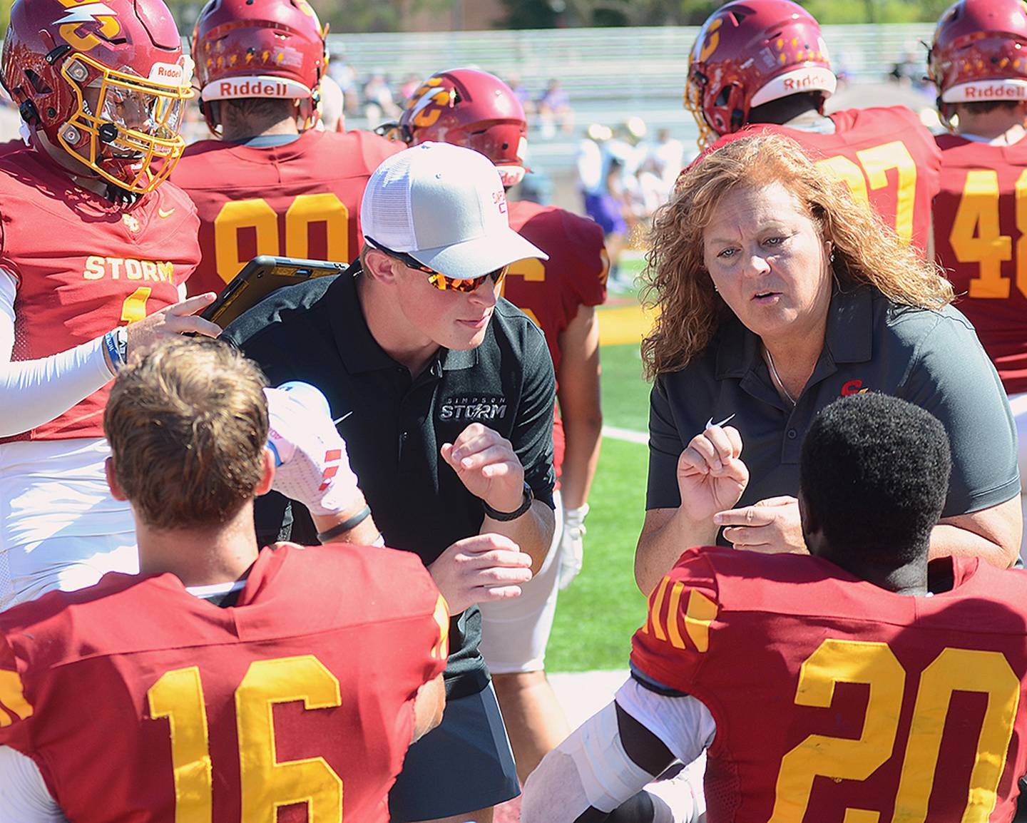 Briley Hayes (left) communicates with Simpson running back Demarico Young (20) after an offensive series, with the help of Young's hearing-impaired interpreter Dawn Habhab.