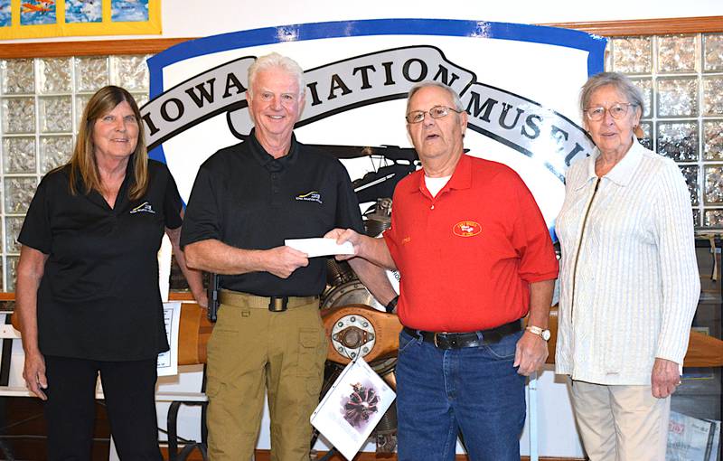 Iowa Aviation Museum's Greg and Kris Schildberg (left) and board member Linda Sidey (far right) receive a donation from Early Wheels of Iowa Past President Forrest Harmsen as the group, best known for organization Greenfield's annual swap meet, is dissolving.