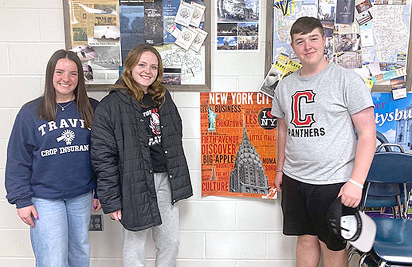 Students who were part of the wreath laying ceremony at Arlington Cemetery were, from left, Lilly James, Taylor Smith and Dylan Dornack. Not pictured, Lila Berning. They are shown by a bulletin board of mementos from trips to Washington, D.C. and New York City in Todd Jacobson's classroom.