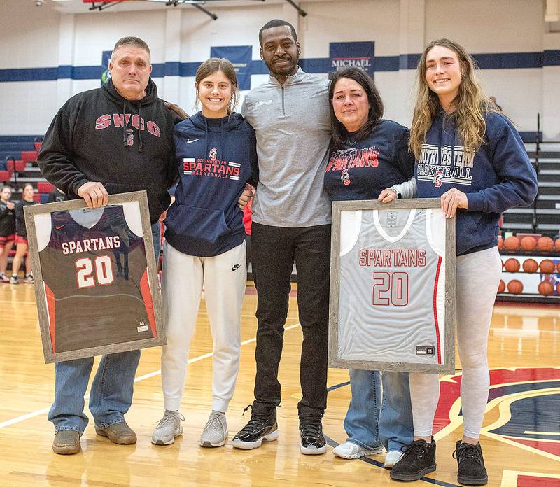Southwestern coach Darian Wingate (center) is shown with family members of the late Maddie Stewart, former Spartan player whose No. 20 jersey was retired prior to Monday's game. Her parents Kevin Stewart and Julie Shields were presented framed jerseys, joined by Maddie's sisters Dannie (left) and Samantha (right) at the presentation.