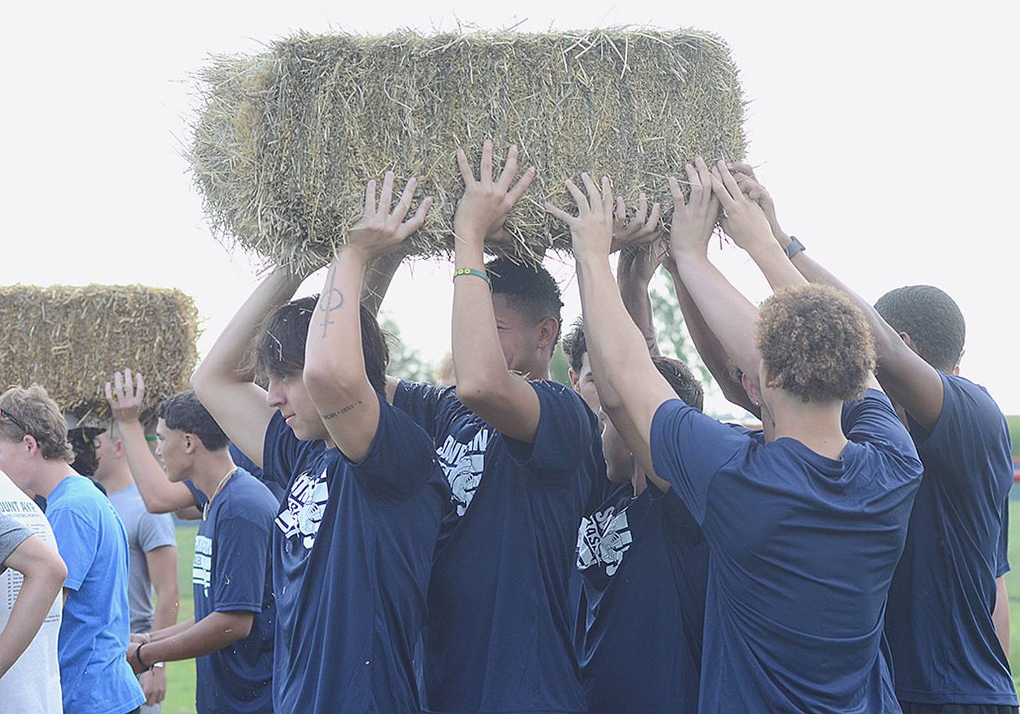 Athletes work together to perform a task moving hay bales in one of Friday's physical challenges promoting teamwork.