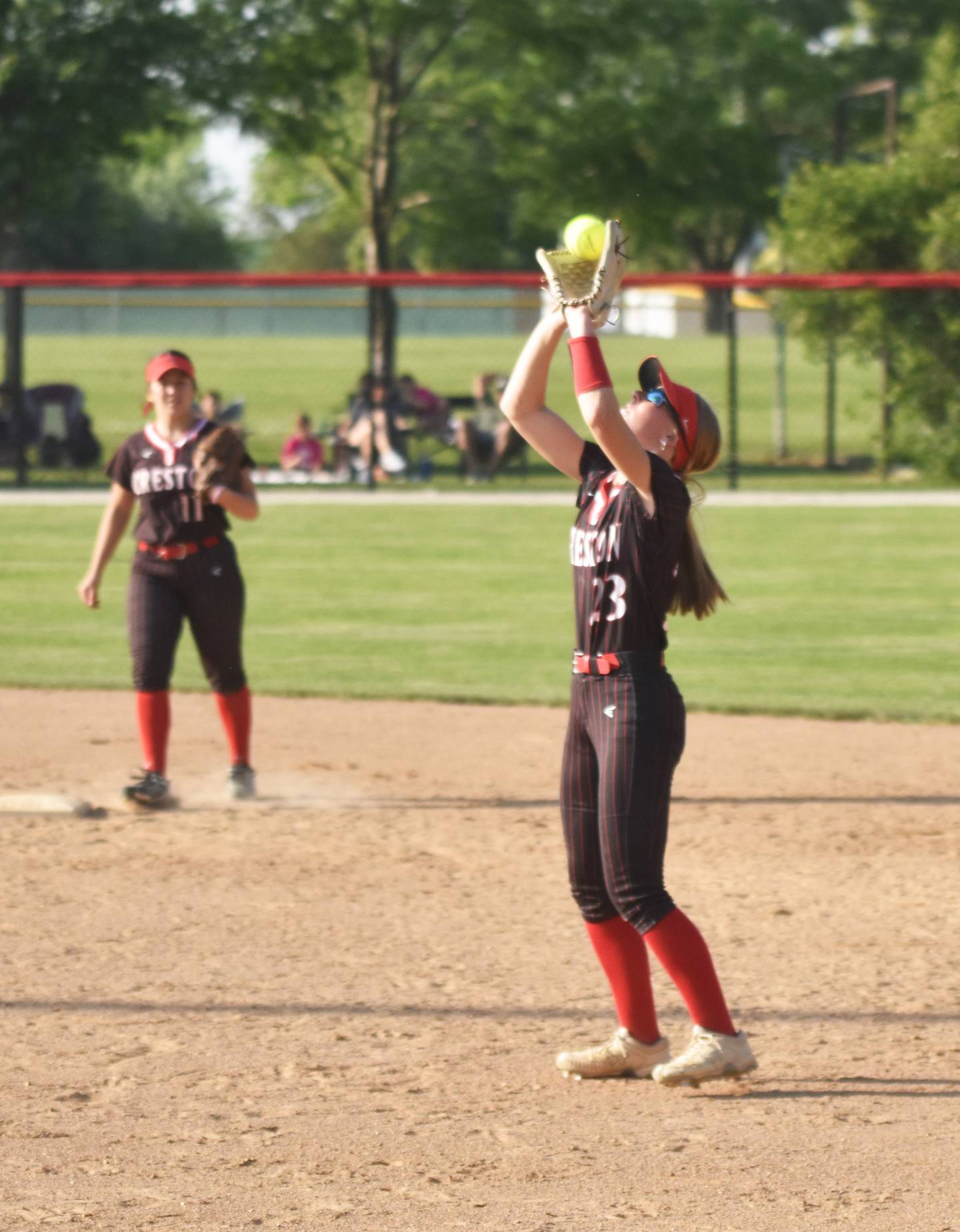 Second baseman Avery Staver catches a pop fly while shortstop Mila Kuhns covers second base.