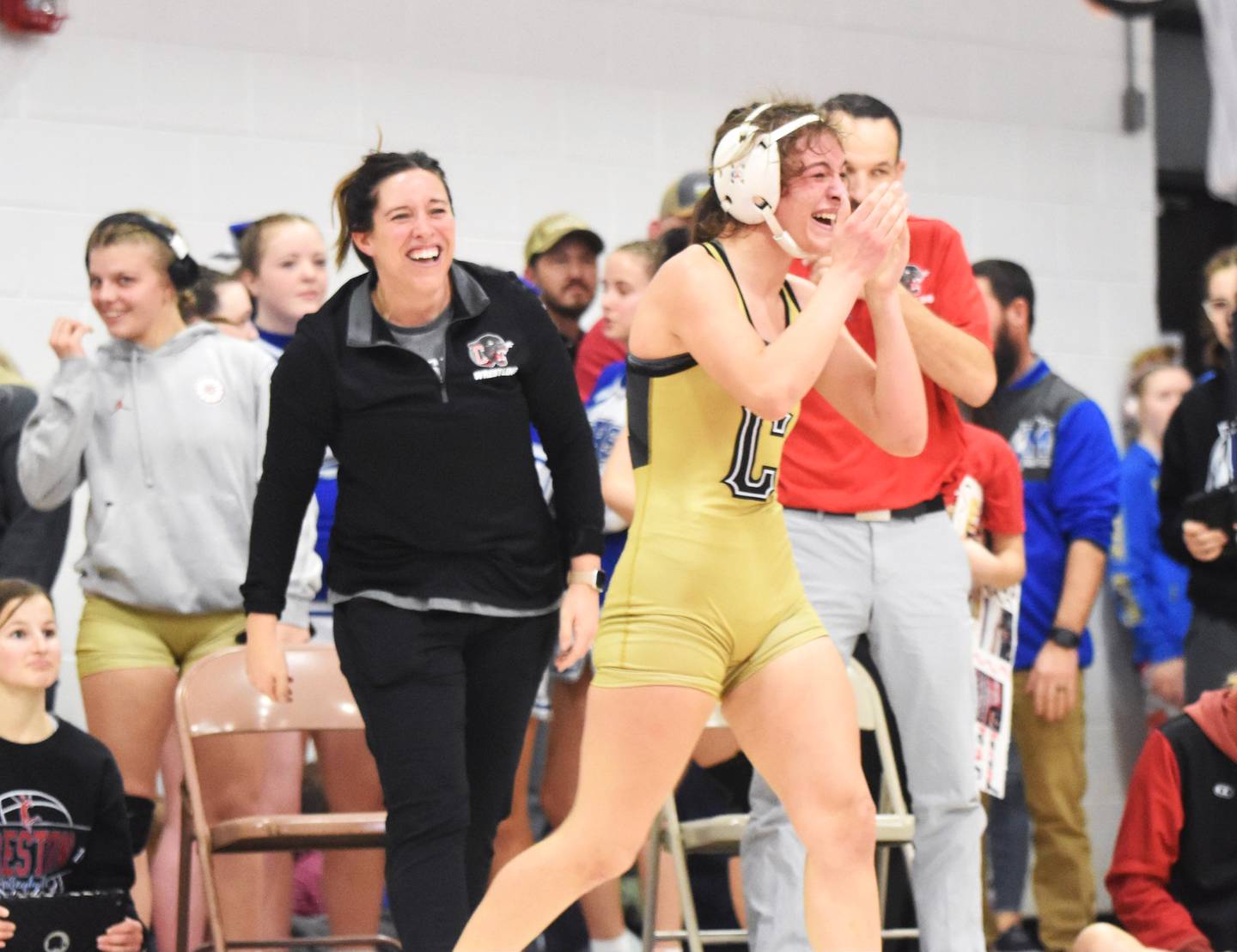 Creston freshman Karlie Kruse celebrates after winning a 125-pound regional wrestling title Friday at Central Decatur. Coaches Maggie Arnold and Mario Galanakis are behind.