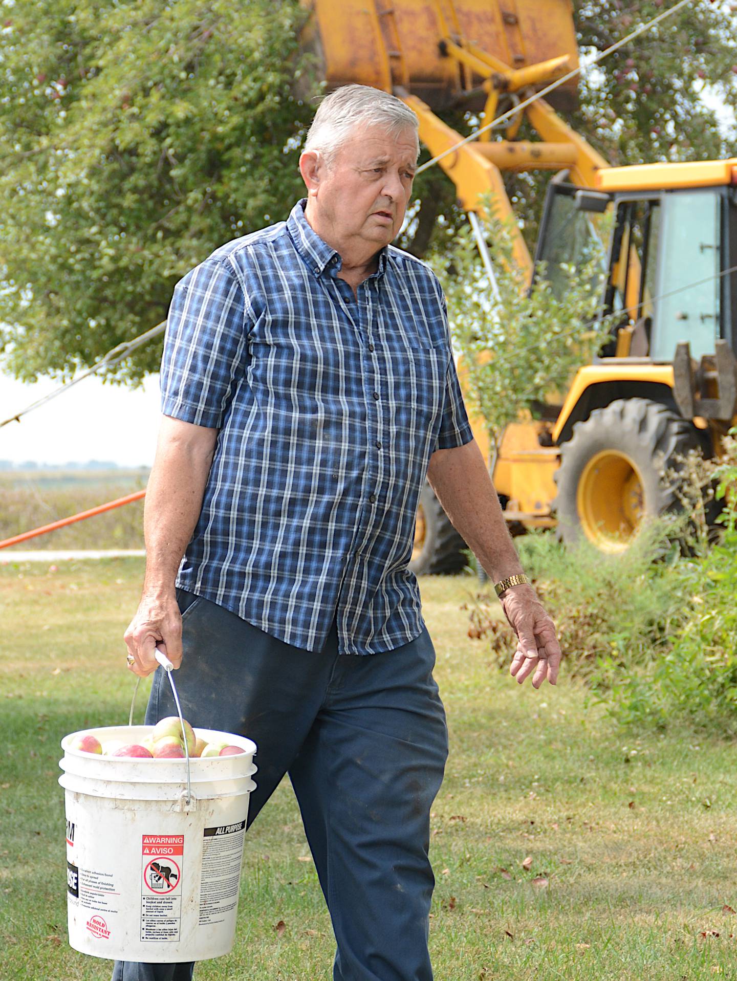 Larry Joe Vandewater carries a bucket of apples from the tree to the apparatus used to make apple cider recently during a cider making event at his farm.