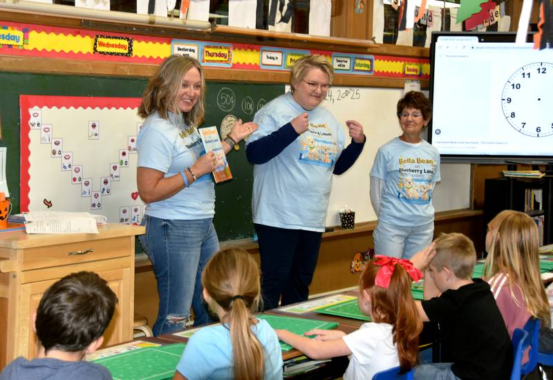 Terri Stephens-Higgins, left, author of “Bella Bean on Blueberry Lane” introduces her doctor, Dr. Karen Krogstad, to second graders at St. Malachy.