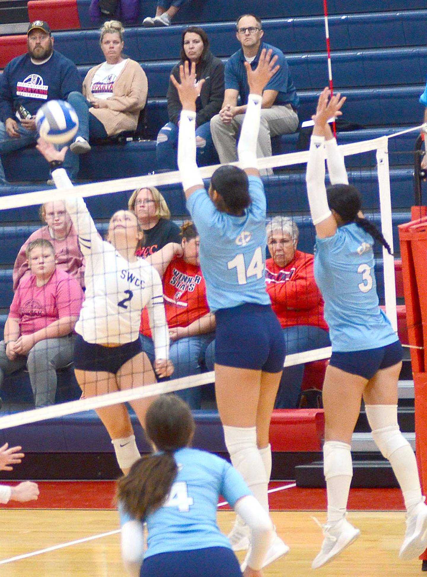 Southwestern's Meredith Gettings hits past the block attempt of Iowa Central's Araya Garrison (14) and Mercedes Madlock (3).
