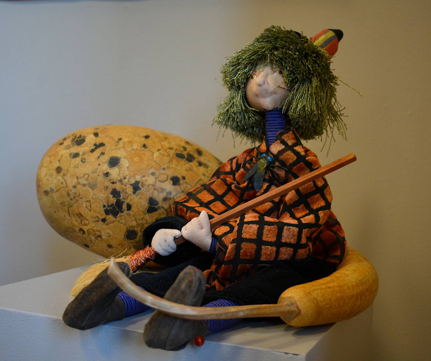 A witch stitched through quiltmaking techniques sits on a column in the Quilt Rebels exhibit.