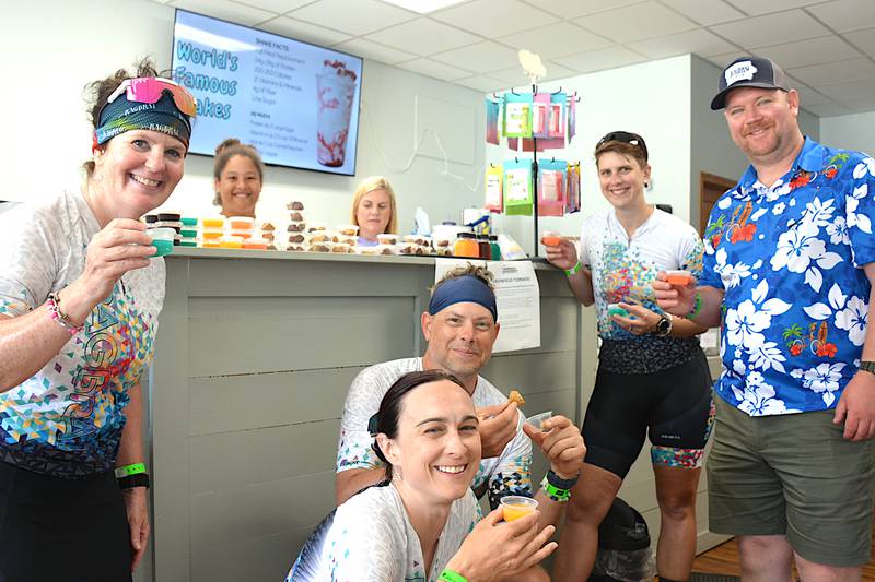 Riders on RAGBRAI's route inspection ride try out energy drink samples at NV Nutrition on the Greenfield Square. After getting a police escort into town, the riders checked out Moe's RBF, NV Nutrition and other attractions.