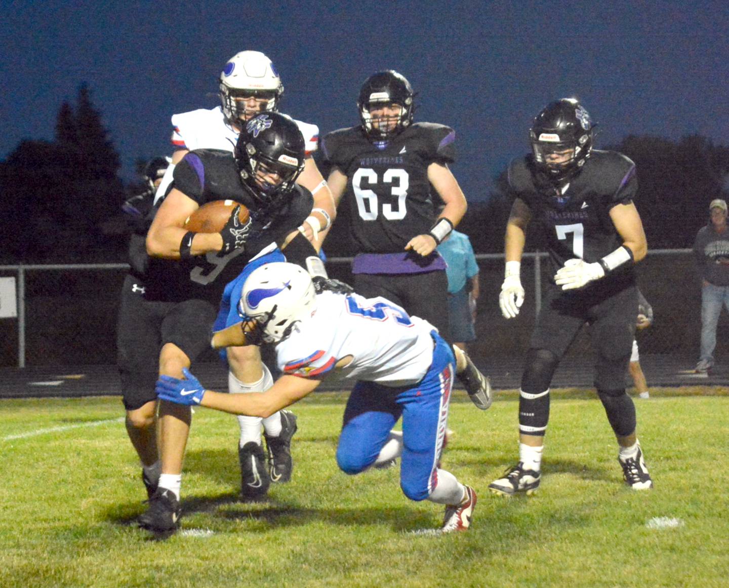 Wolverine junior Caleb Christensen stiff arms an AHSTW tackler on a play during last Friday's homecoming game in Greenfield.