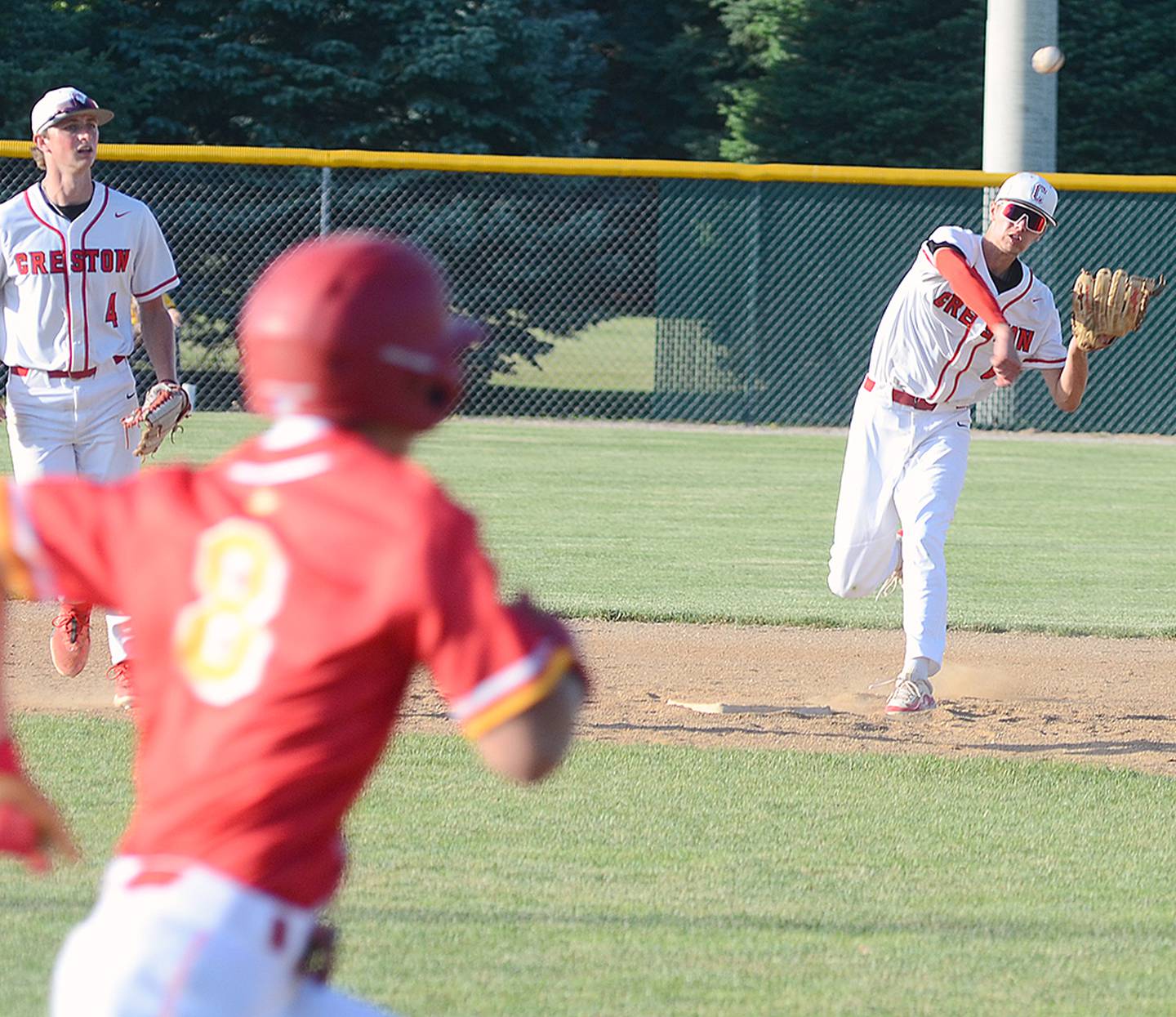 Creston second baseman Dylan Hoepker throws out a runner at first base after fielding a groundball in Creston's 9-2 win over Kuemper Catholic Monday. Hoepker pitched a one-hit shutout in the second game with 12 strikeouts in the 4-0 victory.