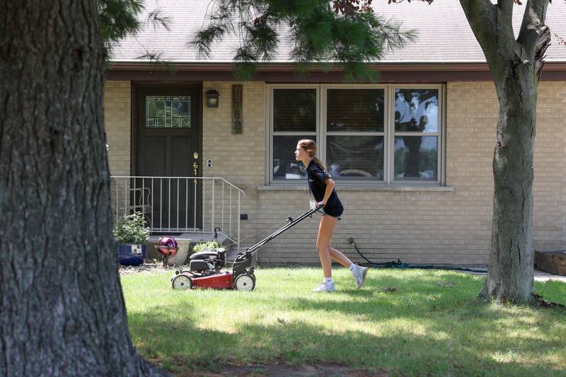Aubrie Coughlan, 13, of Kankakee, mows the grass at a project site in Bourbonnais on July 22, 2025, during the 9th Camp MOSH, a week-long volunteer service camp from Maternity BVM parish. Coughlan, a soon-to-be 8th grader at Bishop McNamara, participated for the first time and said she found the work meaningful.